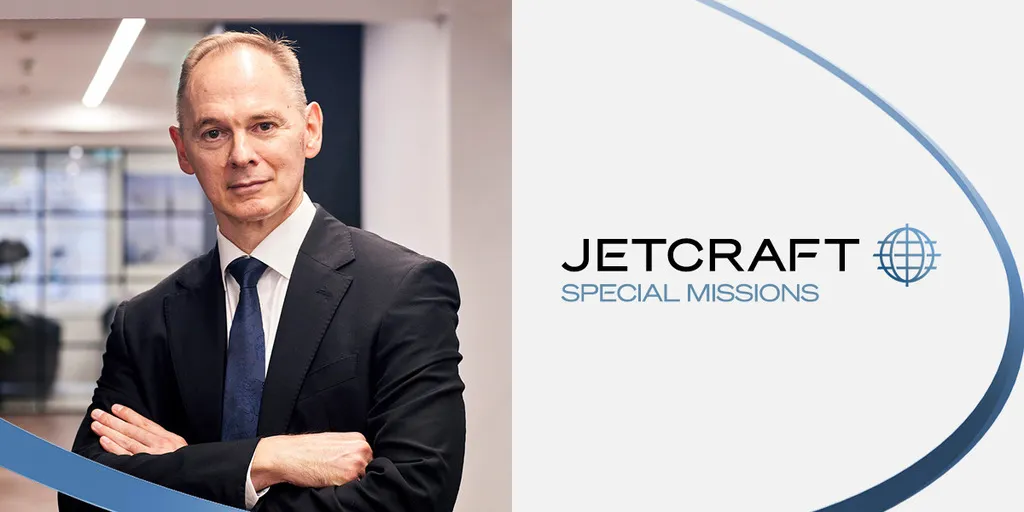 Homem caucasiano careca em um terno escuro com os braços cruzados, posando ao lado do logotipo JETCRAFT SPECIAL MISSIONS.