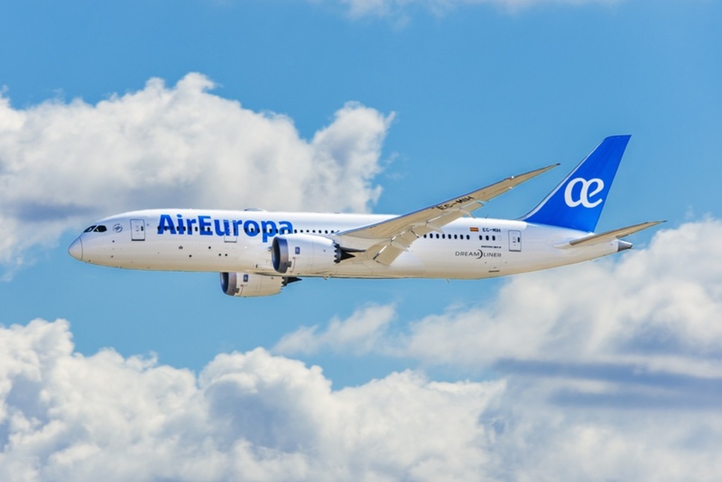 Aeronave Boeing 787 da Air Europa em pleno voo. Fuselagem branca com detalhes em azul, voando acima de uma camada de nuvens cumulus. O céu está limpo e a iluminação é diurna e clara.