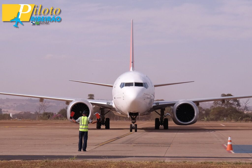 Aeronave Boeing 737 MAX sendo balizada por um funcionário no pátio do Aeroporto de Ribeirão Preto (SBRP). Imagem diurna com foco frontal no nariz e nas grandes turbinas do avião.